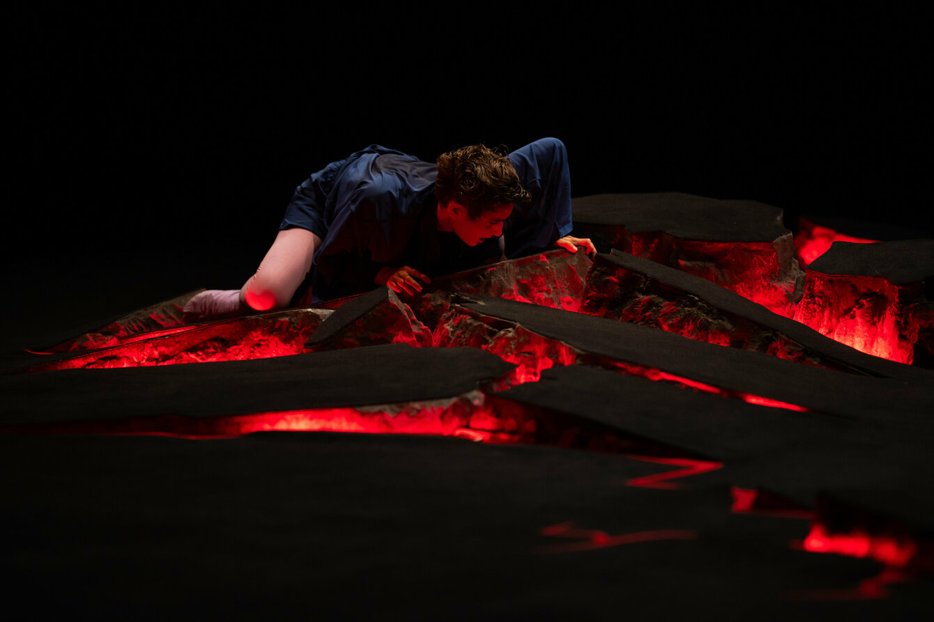 Eine Person bewegt sich in einem Bühnenbild, das wie Lava aussieht