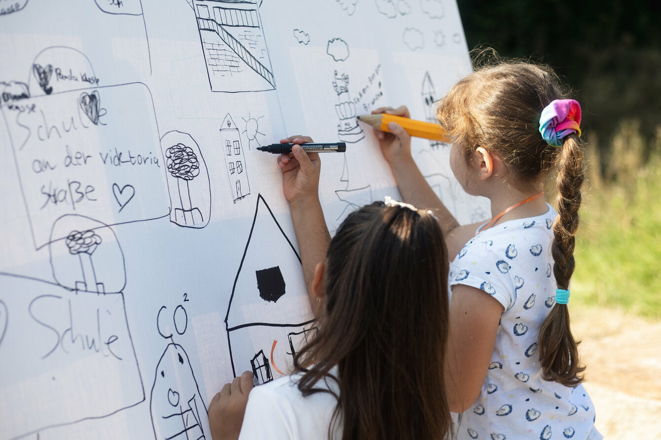 Zwei Kinder von hinten, die auf eine Weiße Leinwand malen