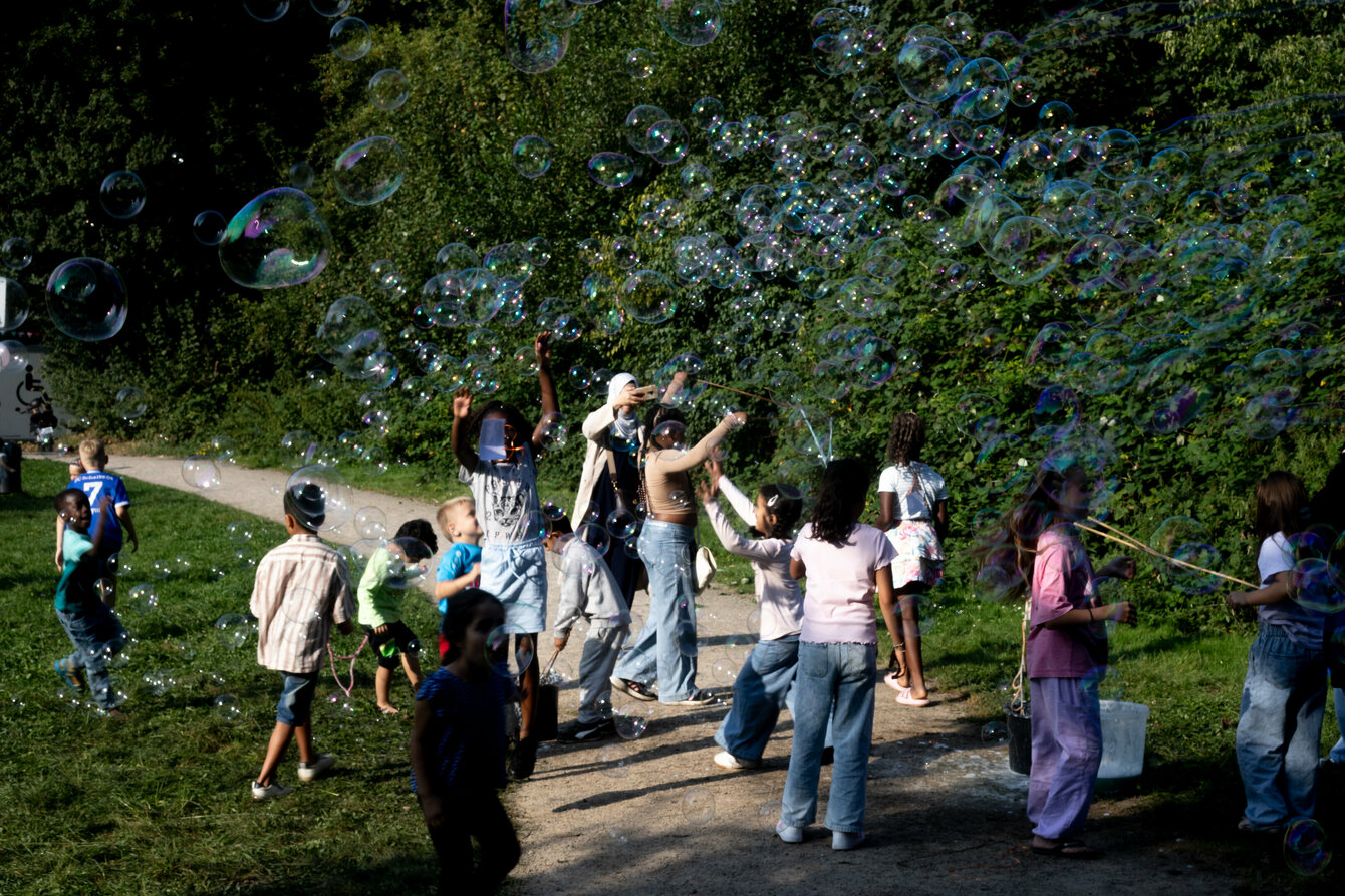 Eine Wiese mit vielen Kindern, die mit Seifenblasen spielen