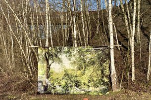Das Bild eines Waldes auf Leinwand hängt zwischen zwei Bäumen in einem Waldstück