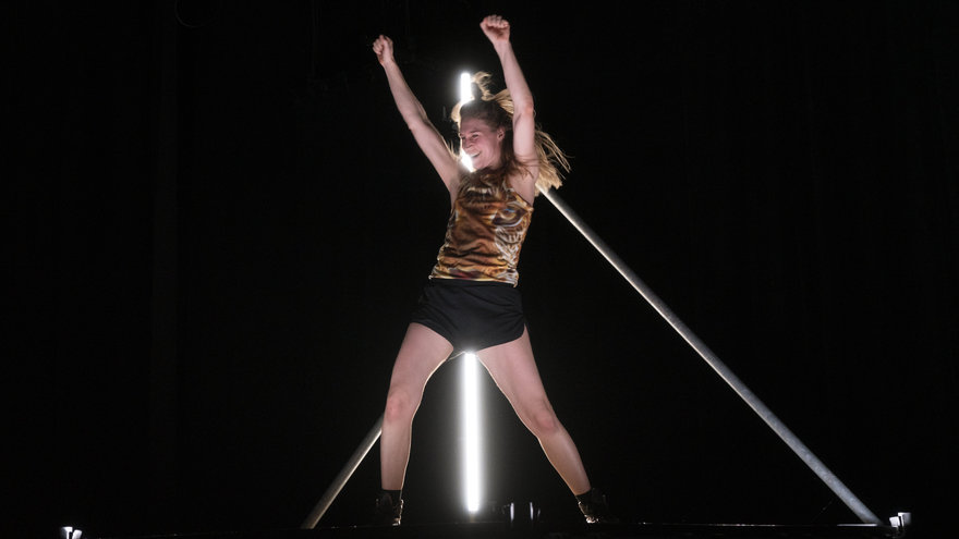 Mette Ingvartsen tanzt auf einer Empore, im Hintergrund ein Neon-Leuchtstab.
